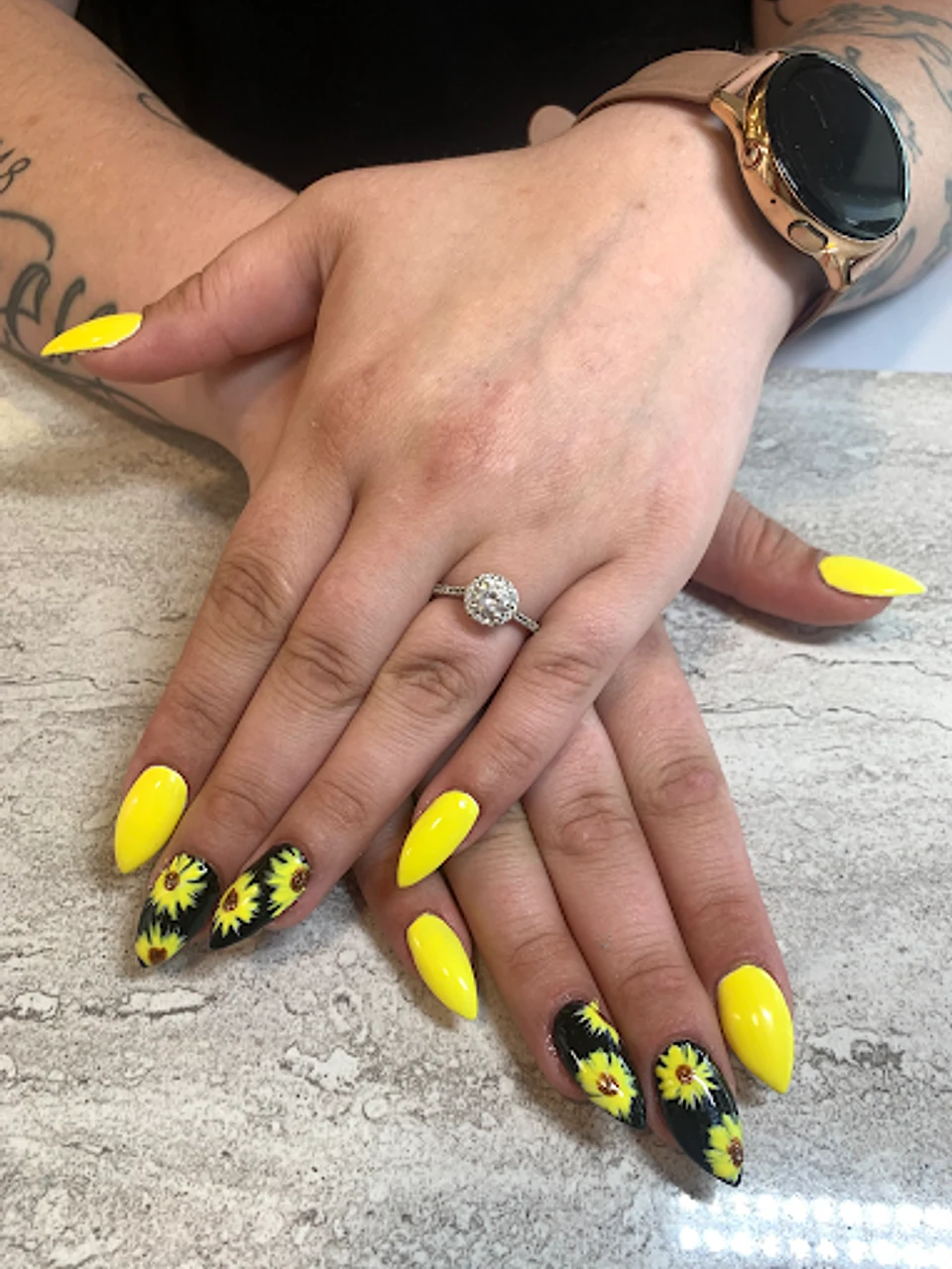 Bright yellow almond-shaped nails with sunflower accent nails on ring fingers