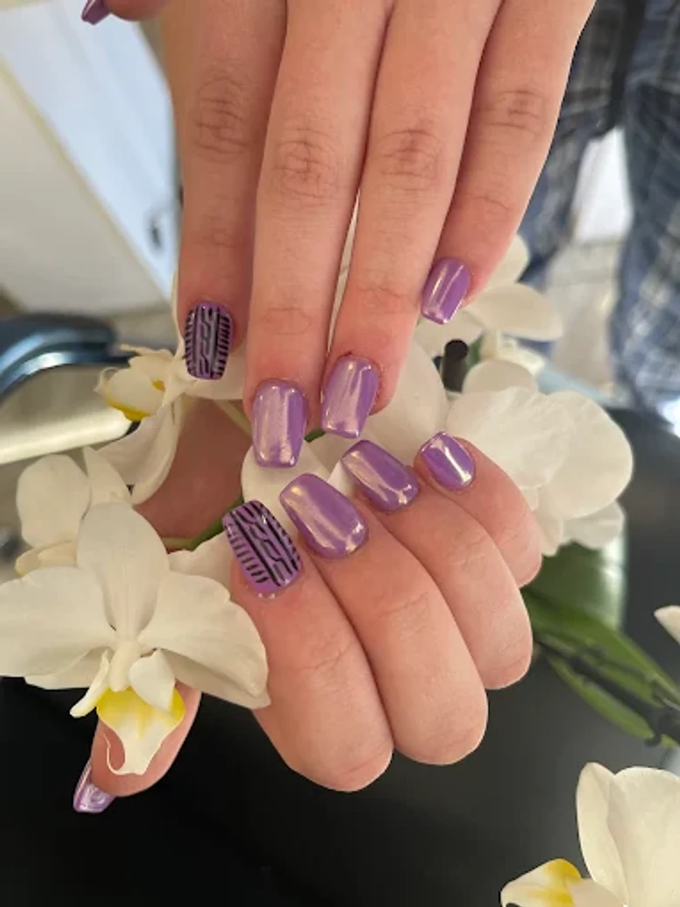 Lavender chrome nails with dark tribal pattern accent nails styled with white orchids