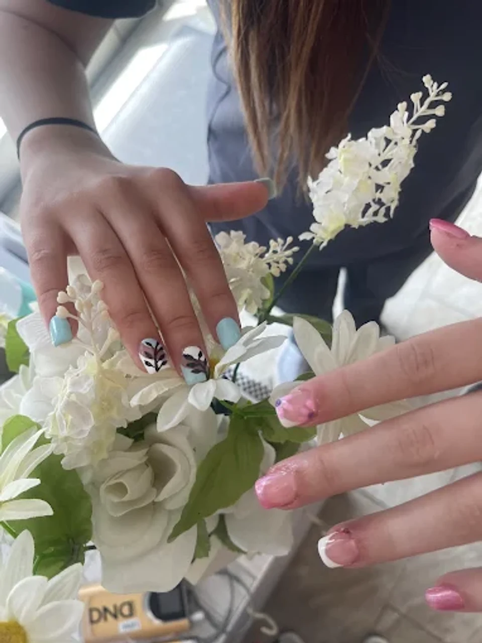 Two nail designs: mint green with botanical accents and pink french tips with glitter