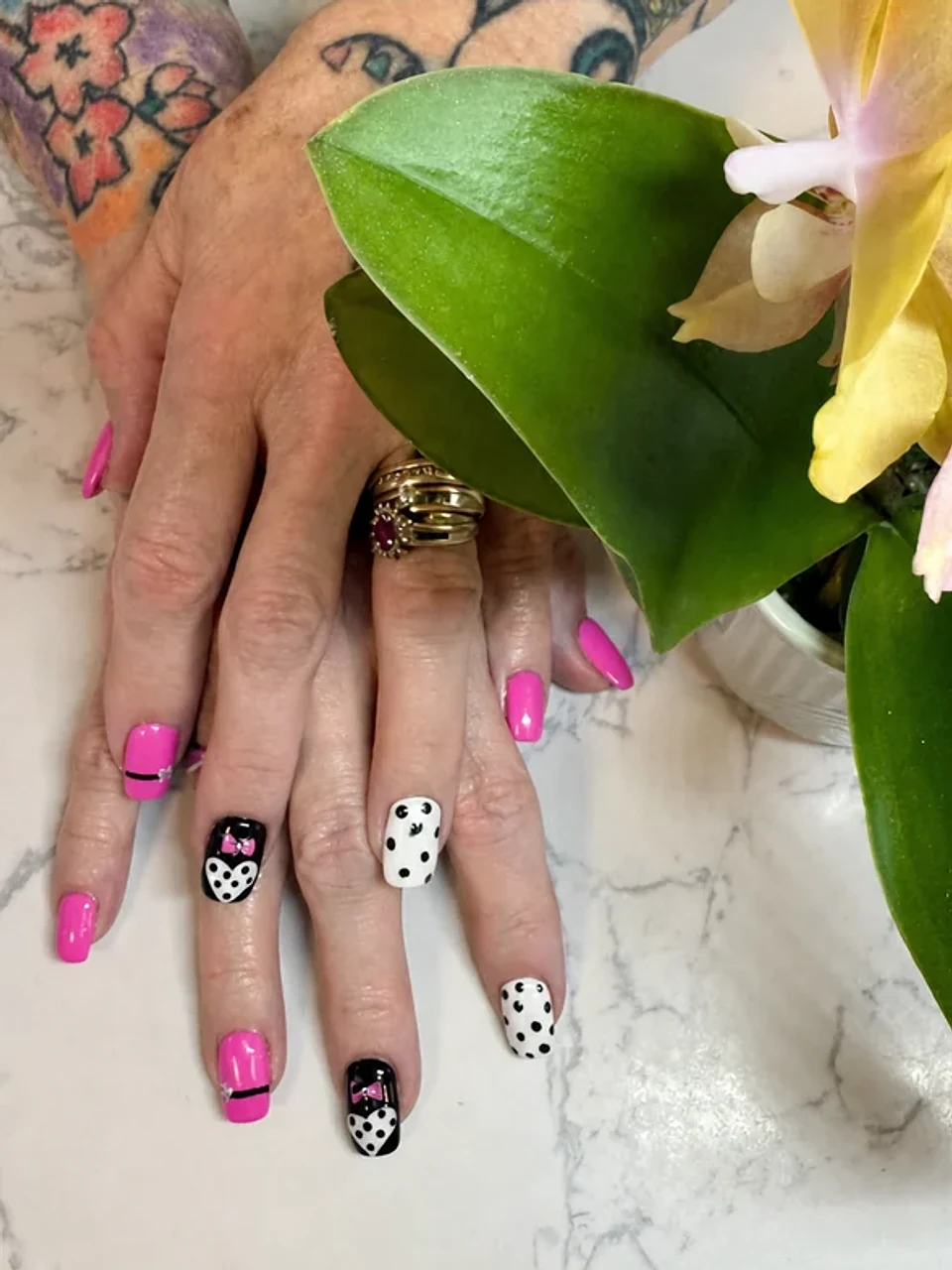 Bright pink, black, and white nails with bows and polka dots