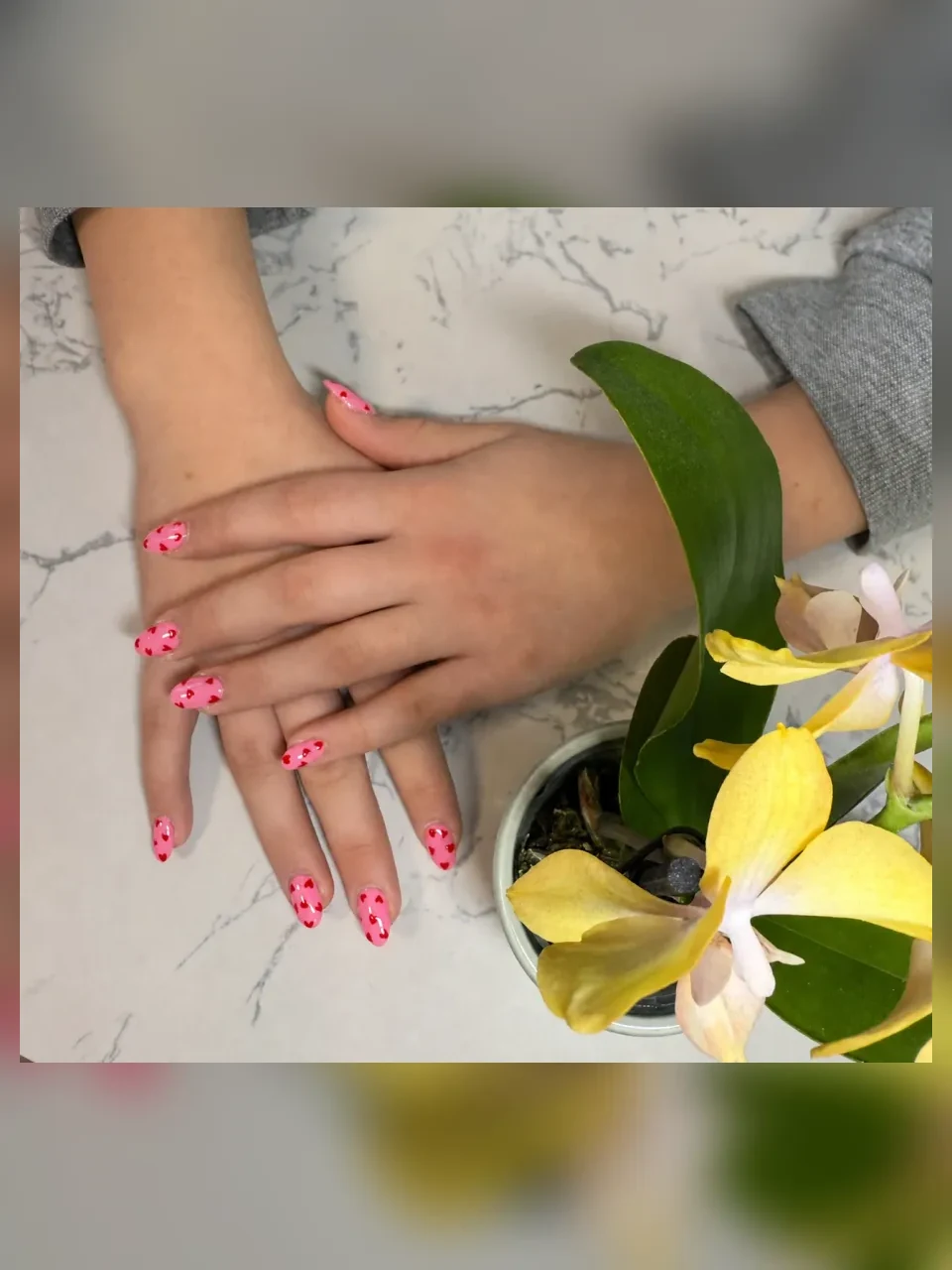 Pink almond nails decorated with small red hearts