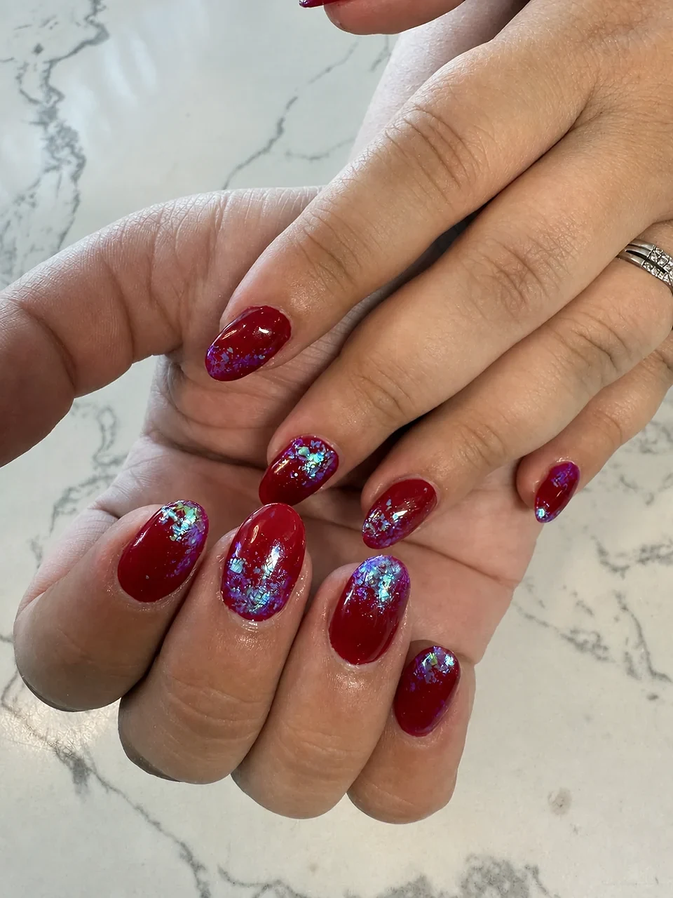 Deep red oval nails with iridescent foil accents